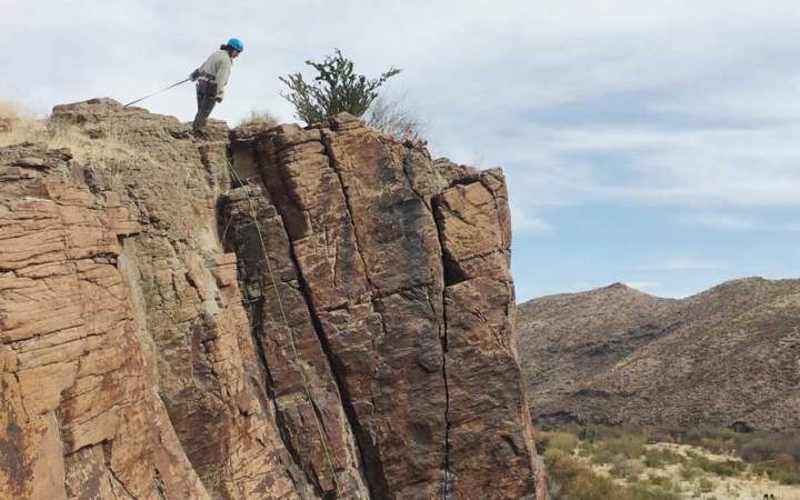 a person looks over a rock ledge while on a rock climbing course with outward bound